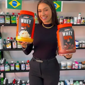 Atendente segura dois potes de whey na loja